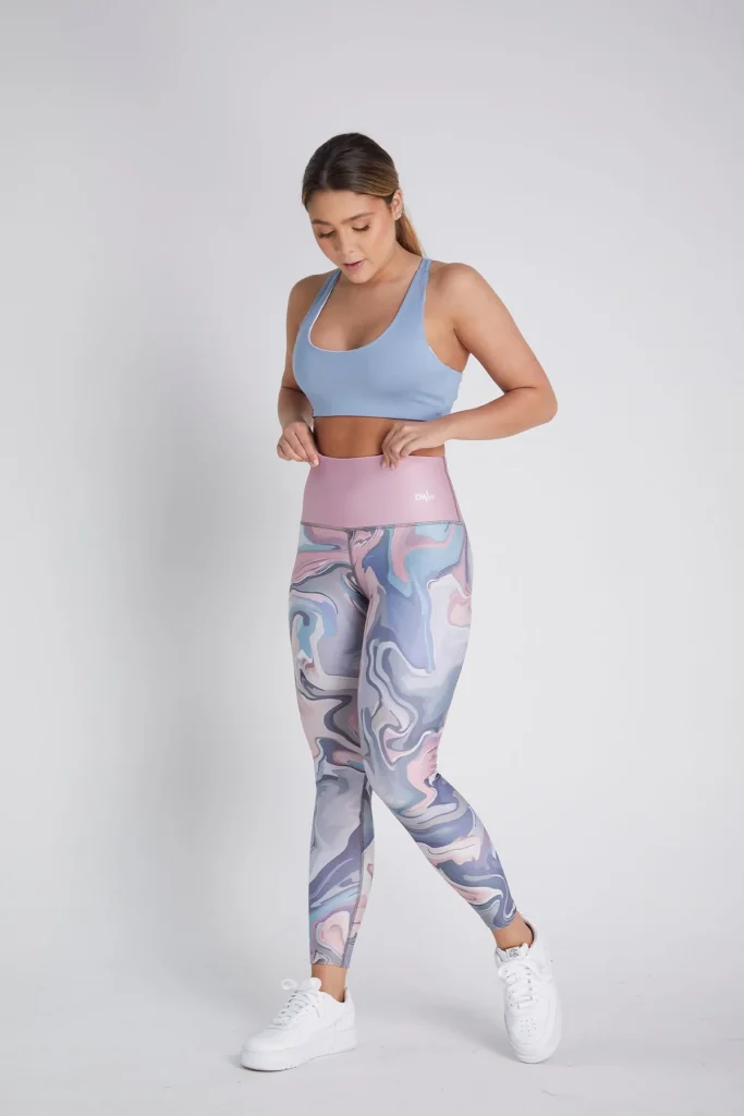 Woman in pastel marble-patterned leggings and blue sports bra, modeling activewear female